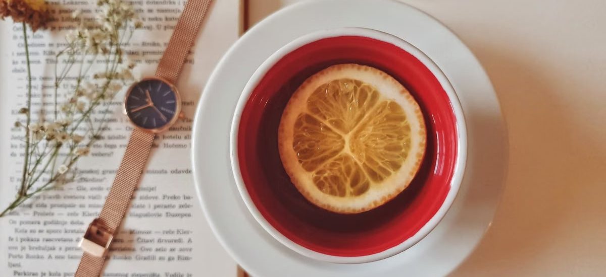 A warm still life of tea with lemon, a watch, and a book, creating a relaxing atmosphere indoors.