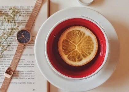 A warm still life of tea with lemon, a watch, and a book, creating a relaxing atmosphere indoors.